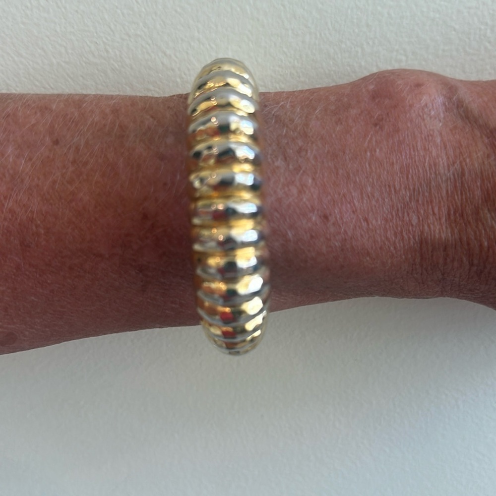 Very pretty gold toned bangle. Opens with side sprinted hinge to easily put on